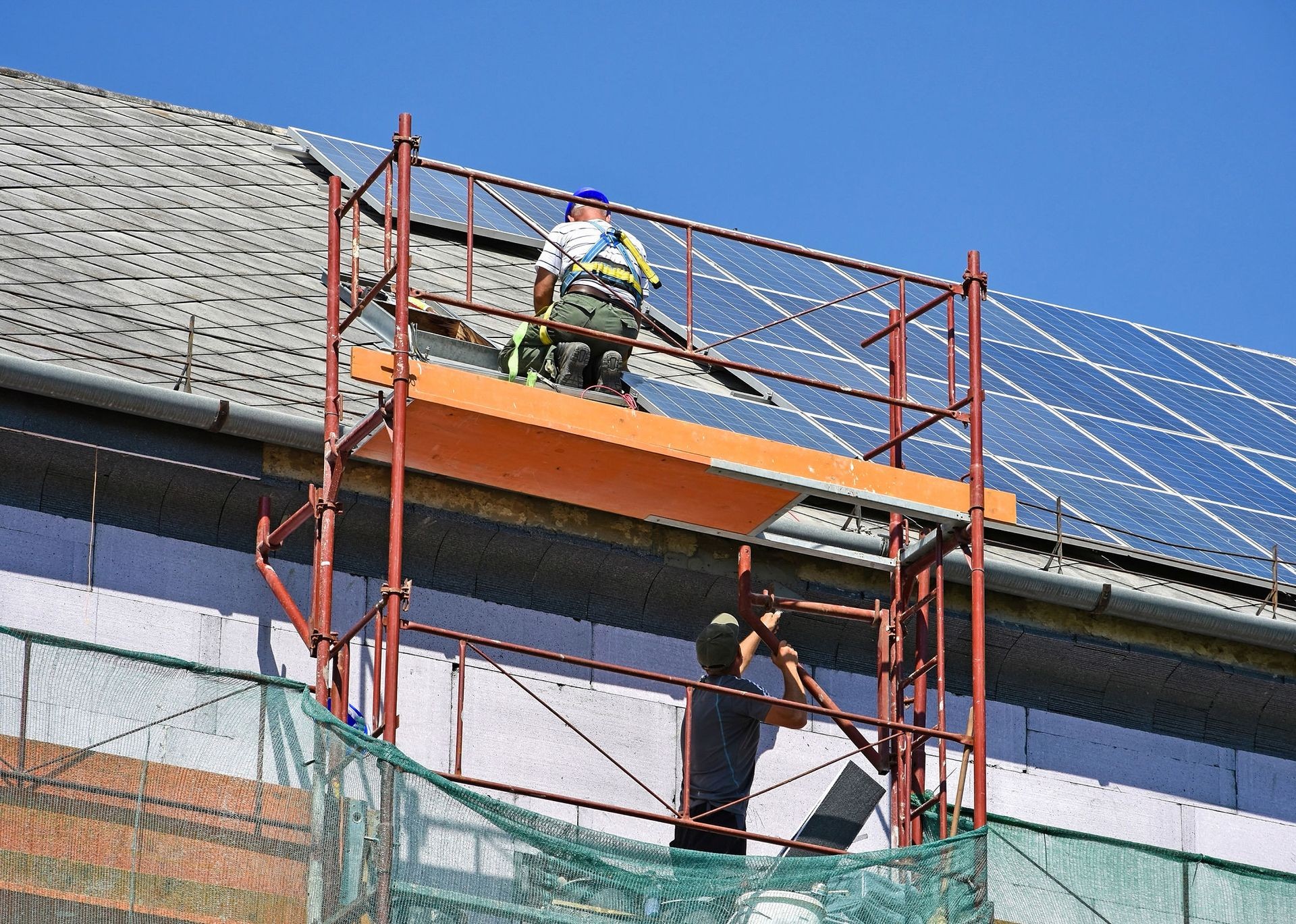 A team of roofers working on a commercial building, installing durable roofing materials with scaffolding and safety equipment for optimal results in a business environment.